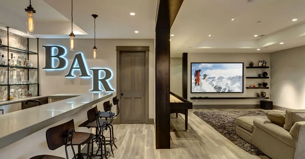 Finished basement with a lighted custom bar, media lounge, and game area