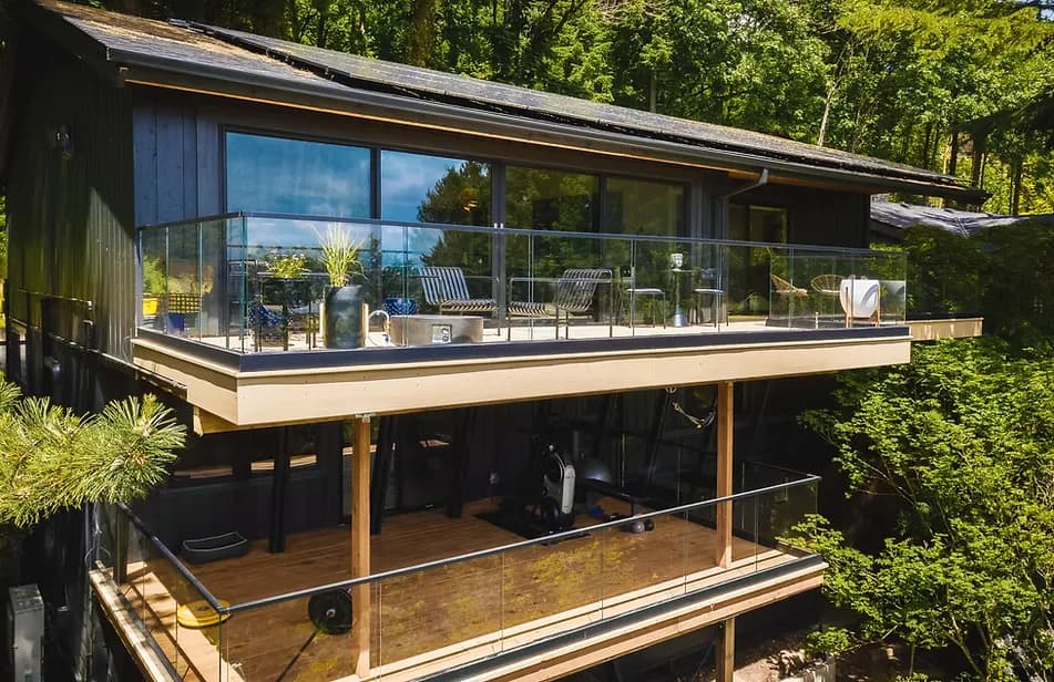 Modern two-level deck addition with glass railings overlooking the trees