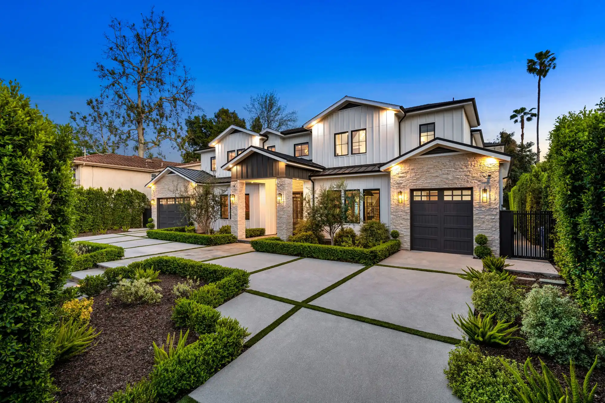 Two-story Portland home addition at dusk with warm exterior lighting and a landscaped front yard