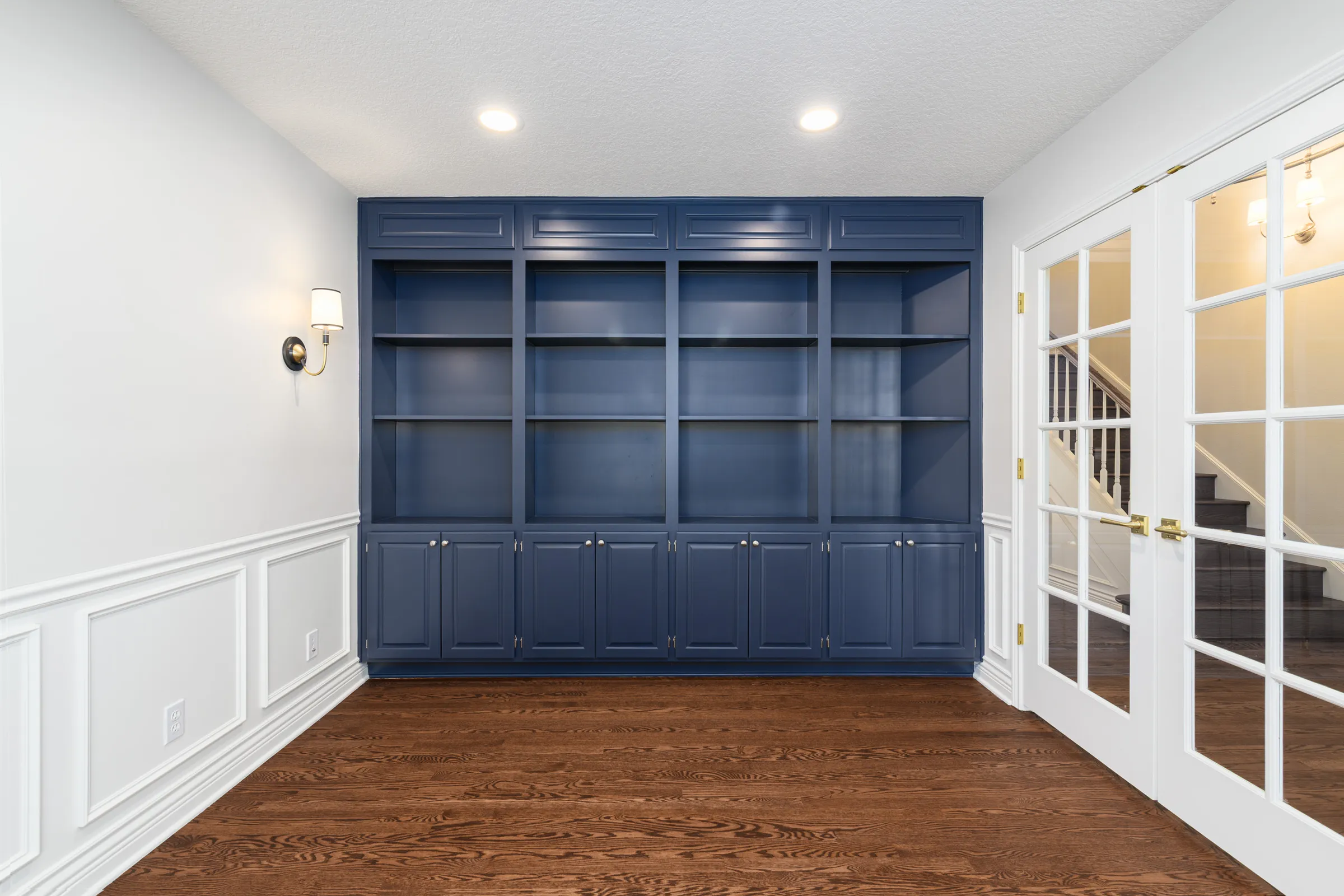 Custom navy built-in shelving beside glass French doors in a remodeled Portland home