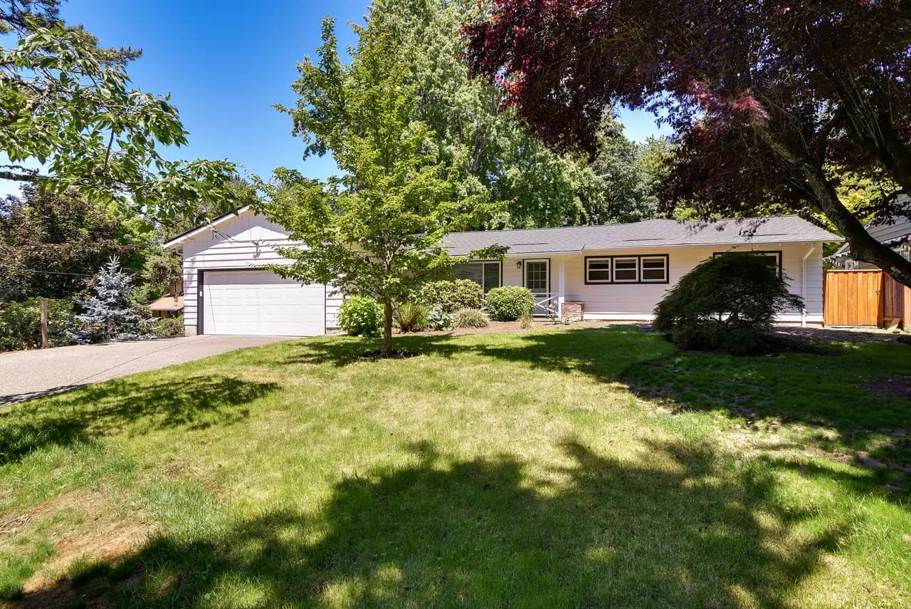 Single-level home exterior with a wide lawn after a whole-home remodel