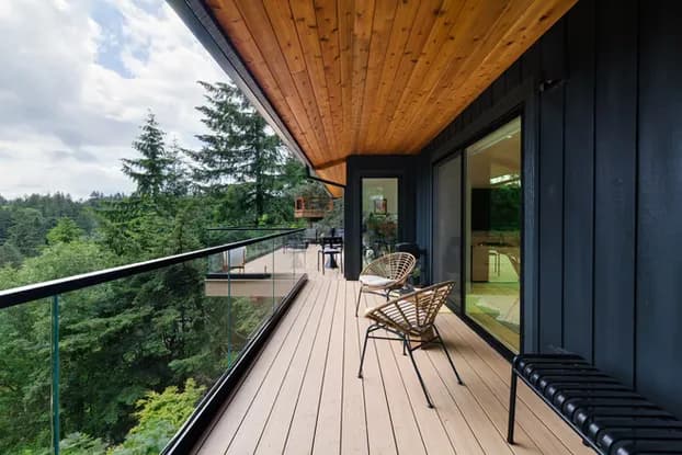 After photo of the finished West Hills deck expansion showing the upper dining and entertaining deck with composite decking, glass panel railings, and warm wood soffit ceiling by Tortoise Construction LLC