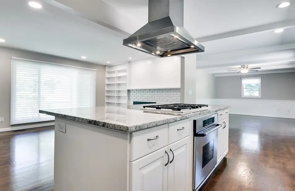 Remodeled open-concept kitchen with white island, granite countertops, stainless range hood, and gas cooktop in a Portland area home by Tortoise Construction LLC